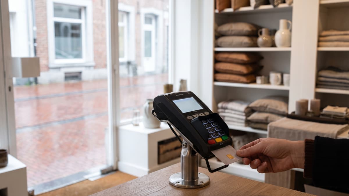 Een klant steekt zijn bankkaart in een betaalterminal op een standaard in een woonwinkel.